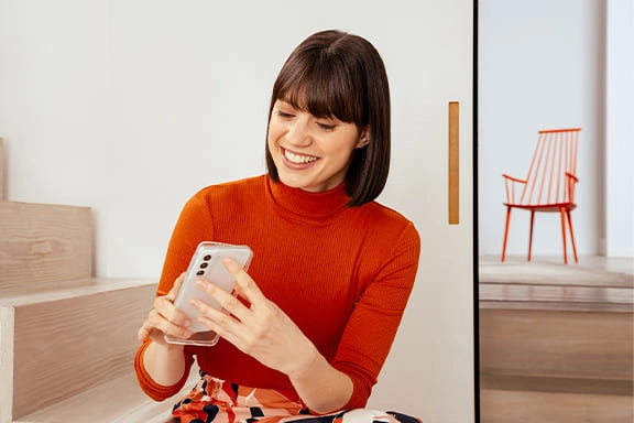 Une femme avec une coque et un portable Samsung dans la main.