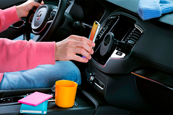 Un iPhone est en charge par induction dans une voiture sur un support fixé sur les fentes de ventilation.