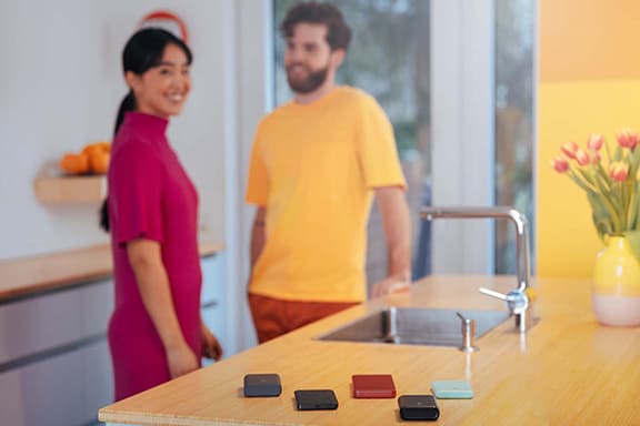 Plusieurs batteries externes sont posées sur un comptoir ; en arrière-plan, des personnes joyeuses