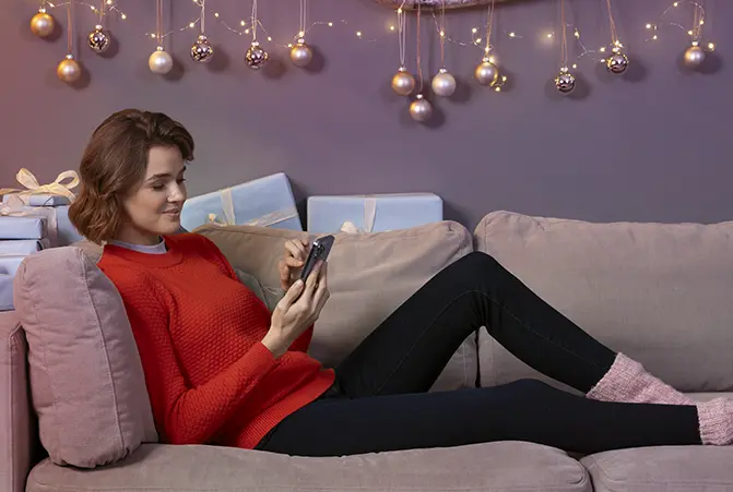 Person liegt mit dem Handy auf dem Sofa.