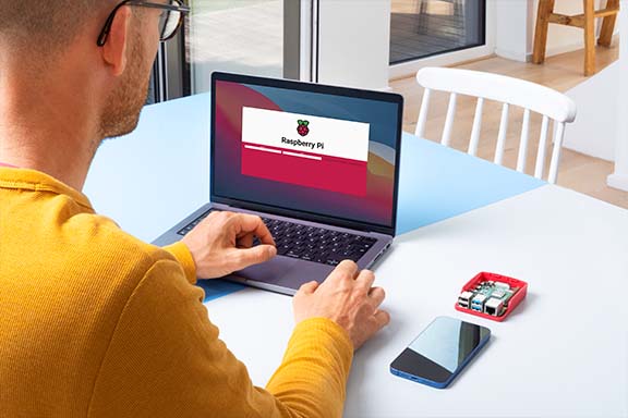 Personne assise à une table avec un ordinateur portable et un Raspberry Pi pour installer Homebridge