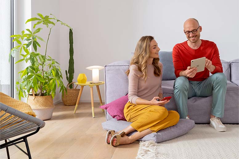 Des personnes dans un salon utilisent un smartphone et une tablette.