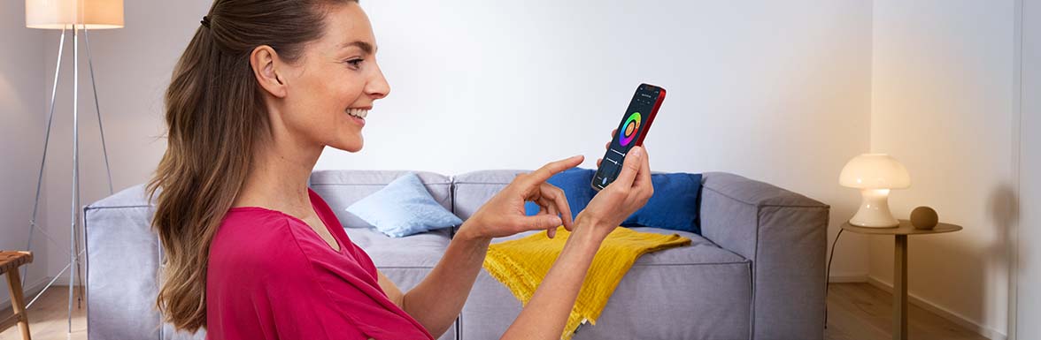 Une femme utilise une application Smart Home sur son smartphone
