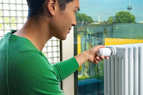 Une personne règle un thermostat.