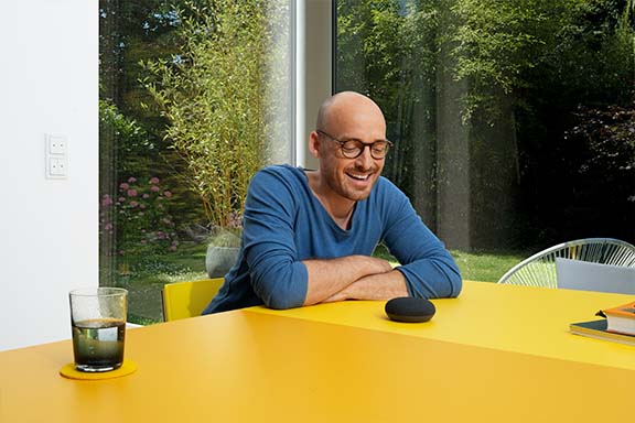 Une personne est devant une enceinte Google Nest